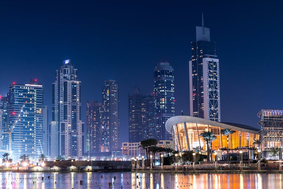 Stunning view of Dubai's illuminated skyline with modern skyscrapers reflecting on water at night.