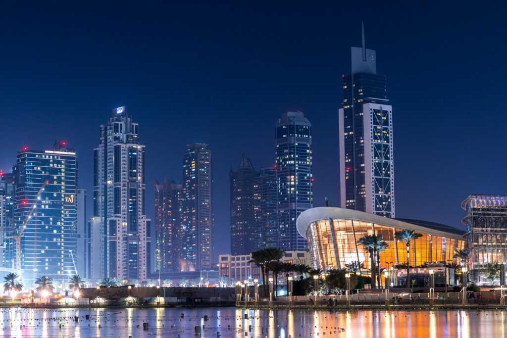 Stunning view of Dubai&#039;s illuminated skyline with modern skyscrapers reflecting on water at night.