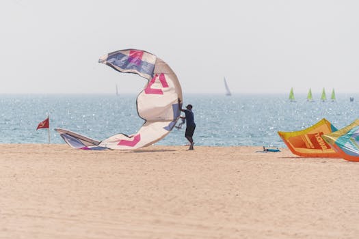 Person enjoying kite surfing on a beach in Dubai, with colorful kites and the sea visible, highlighting free outdoor activities in the city.